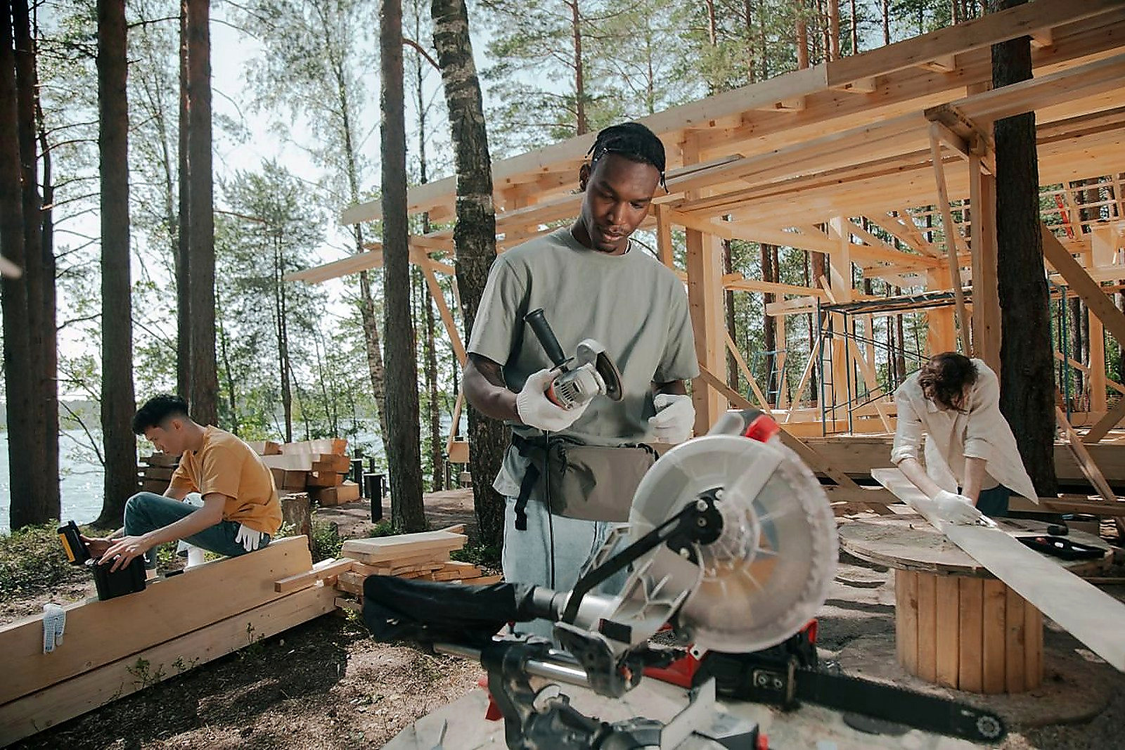 Free Construction crew building a wooden structure outdoors in a forest setting. Stock Photo