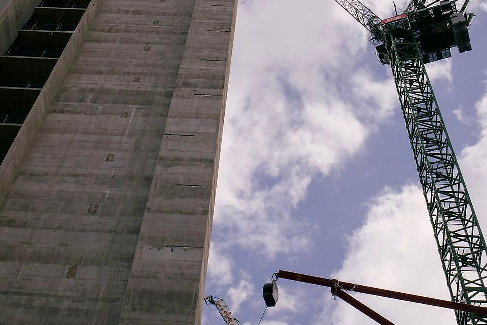 Free Low angle view of skyscraper under construction with cranes against blue sky. Stock Photo