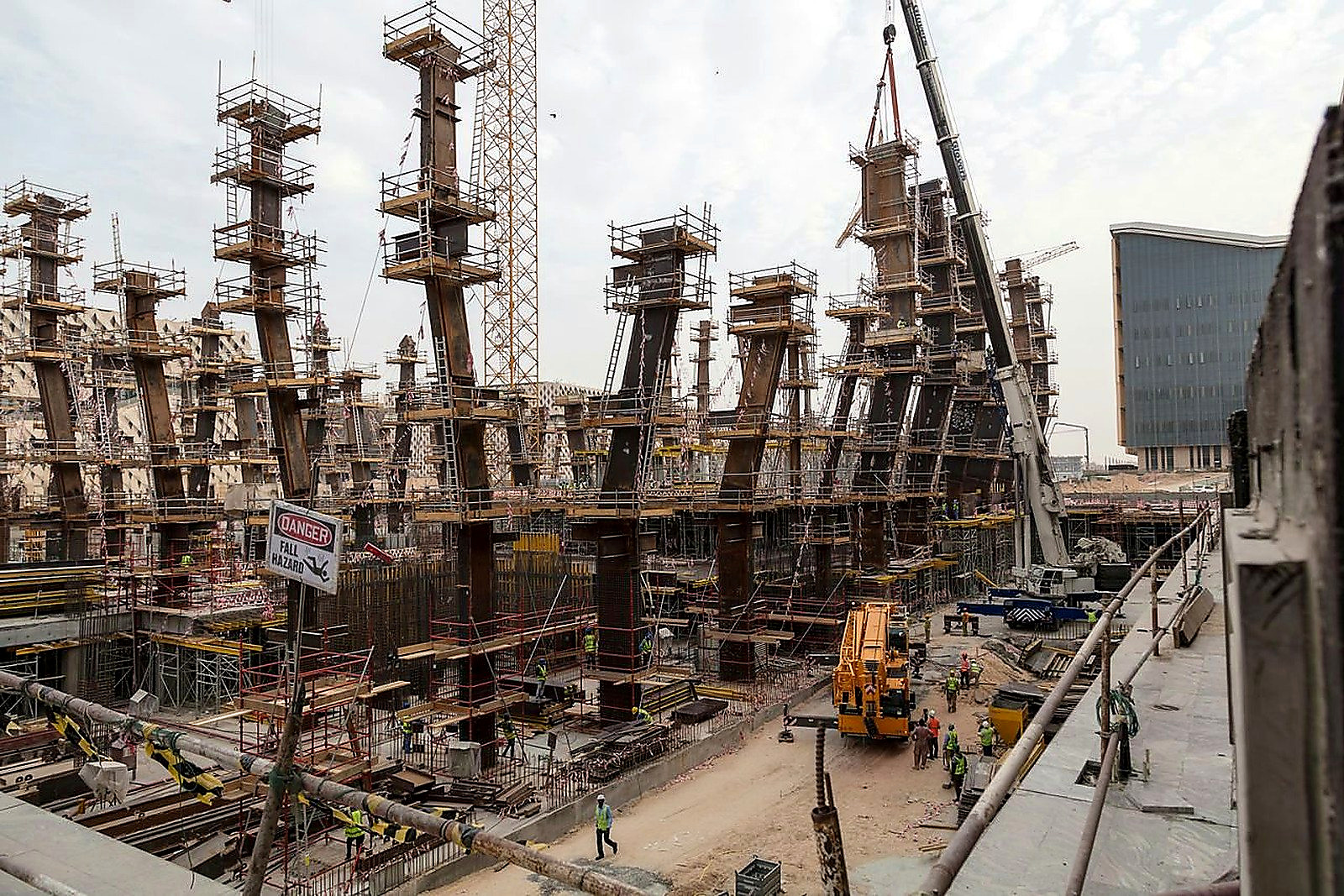 Free A bustling construction site with towering steel frameworks and cranes under a cloudy sky. Stock Photo