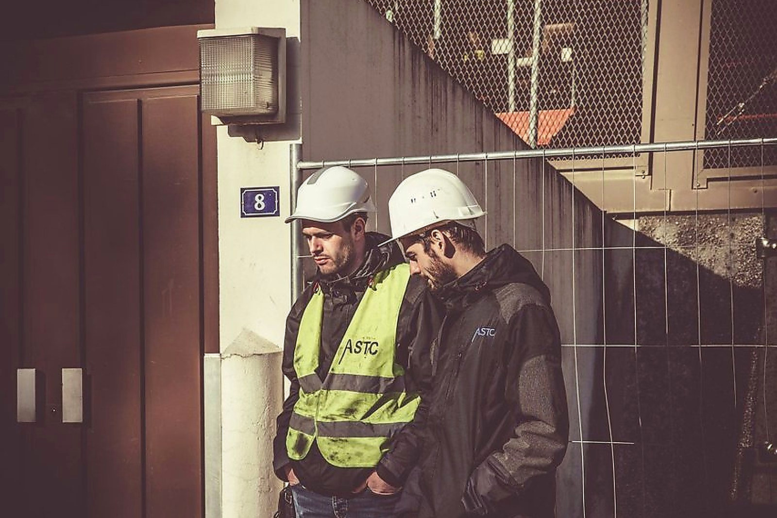 Free Two construction workers in safety gear standing outdoors at a building site, focused on work. Stock Photo